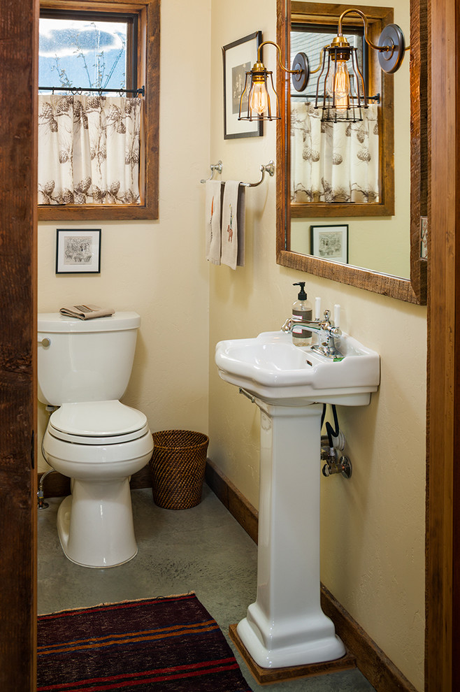 Idée de décoration pour un très grand WC et toilettes chalet avec un lavabo de ferme, un placard à porte plane et sol en béton ciré.