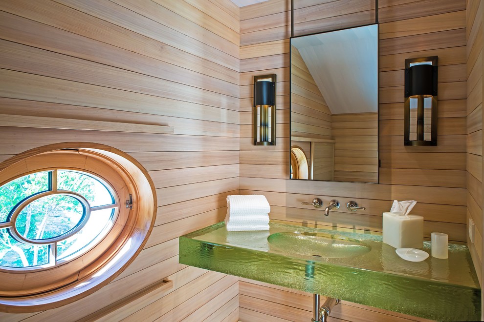 Diseño de aseo costero con lavabo integrado, encimera de vidrio, encimeras verdes y paredes beige