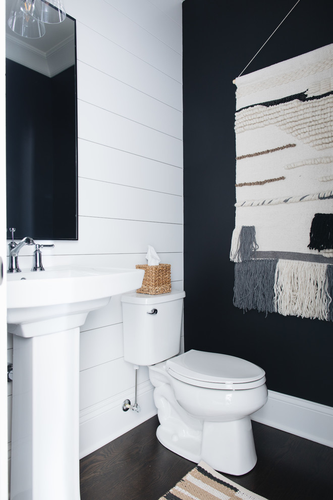 Example of a farmhouse dark wood floor and brown floor powder room design in Chicago with a two-piece toilet, black walls and a pedestal sink