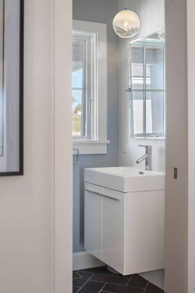 Modelo de aseo clásico renovado de tamaño medio con armarios con paneles lisos, puertas de armario blancas, paredes azules, suelo de pizarra, lavabo integrado y suelo gris