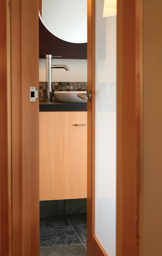 Photo of a small contemporary cloakroom in Seattle with flat-panel cabinets, granite worktops, a vessel sink, light wood cabinets, white walls and black tiles.