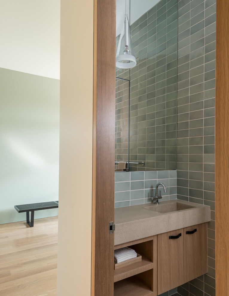 Diseño de aseo contemporáneo pequeño con lavabo integrado, armarios con paneles lisos, baldosas y/o azulejos grises, puertas de armario de madera clara y encimeras beige