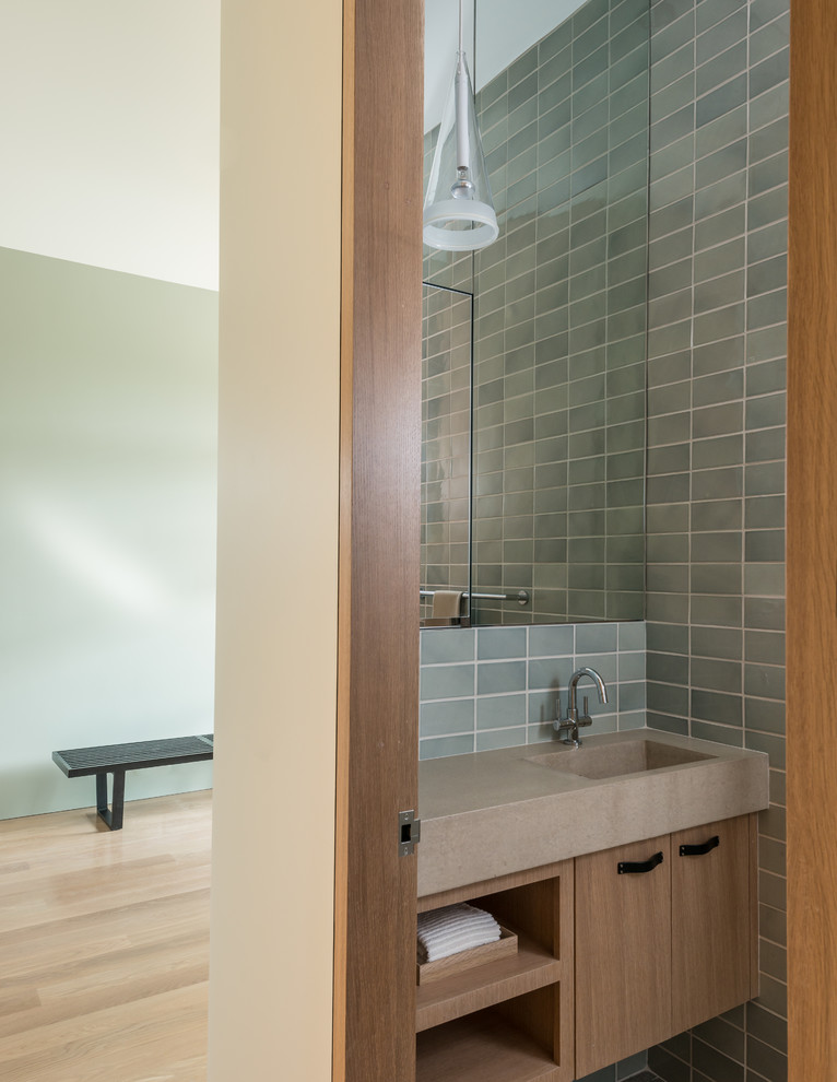 ソルトレイクシティにあるコンテンポラリースタイルのおしゃれなトイレ・洗面所 (一体型シンク、フラットパネル扉のキャビネット、グレーのタイル、淡色木目調キャビネット) の写真