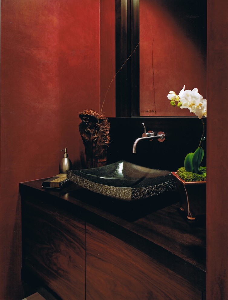 Esempio di un bagno di servizio design di medie dimensioni con ante lisce, ante in legno scuro, WC monopezzo, piastrelle nere, pareti rosse, top in superficie solida e lavabo a bacinella