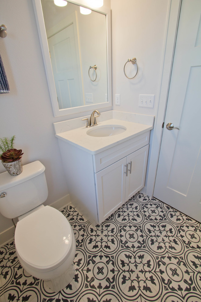Inspiration för små moderna toaletter, med luckor med infälld panel, vita skåp, en toalettstol med separat cisternkåpa, vita väggar, cementgolv, ett undermonterad handfat och flerfärgat golv