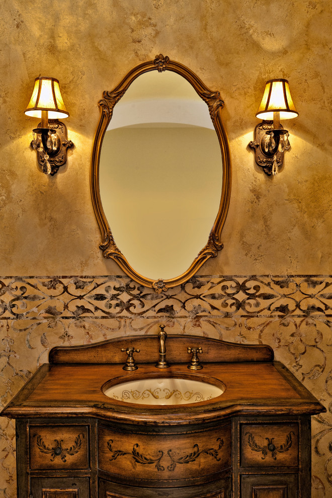 Idee per un piccolo bagno di servizio mediterraneo con consolle stile comò, pareti beige, lavabo sottopiano, top in legno, ante con finitura invecchiata e top marrone