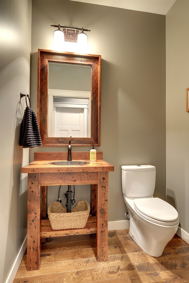 Urige Gästetoilette mit Wandtoilette mit Spülkasten, brauner Wandfarbe, braunem Holzboden, Einbauwaschbecken, Waschtisch aus Holz, braunem Boden und brauner Waschtischplatte in Minneapolis