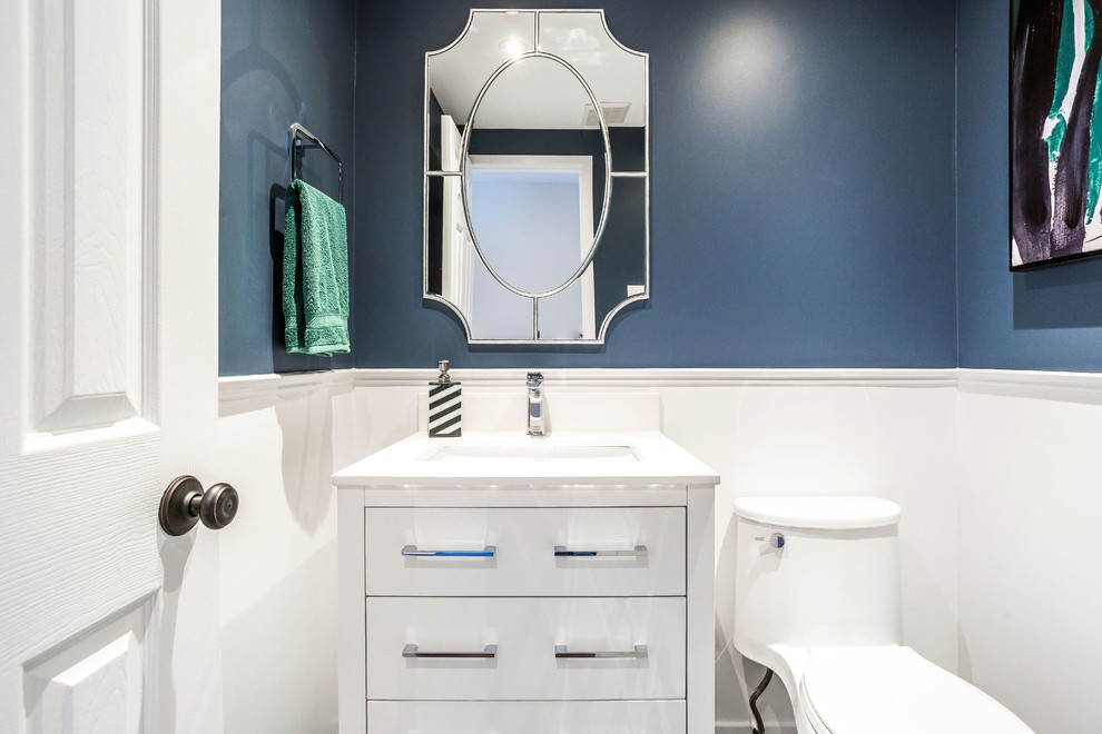 Cette image montre un petit WC et toilettes traditionnel avec un placard en trompe-l'oeil, des portes de placard blanches, WC à poser, un mur bleu, un sol en marbre, un lavabo encastré, un plan de toilette en quartz, un sol noir et un plan de toilette blanc.