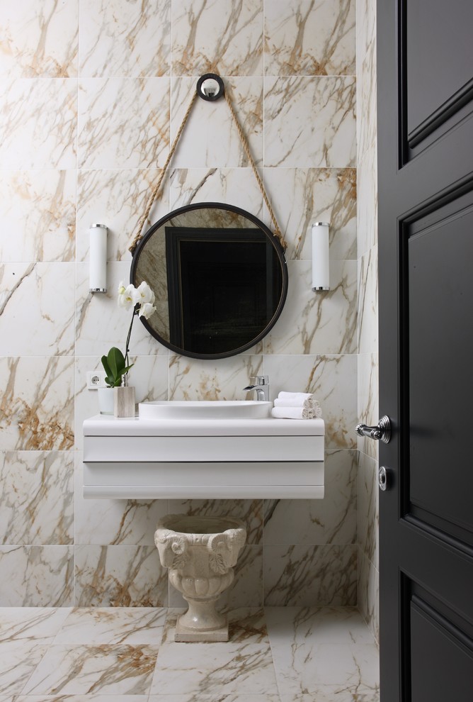 Cette photo montre un WC et toilettes tendance avec un placard à porte plane, des portes de placard blanches, un sol en marbre, un lavabo posé, du carrelage en marbre et un carrelage beige.