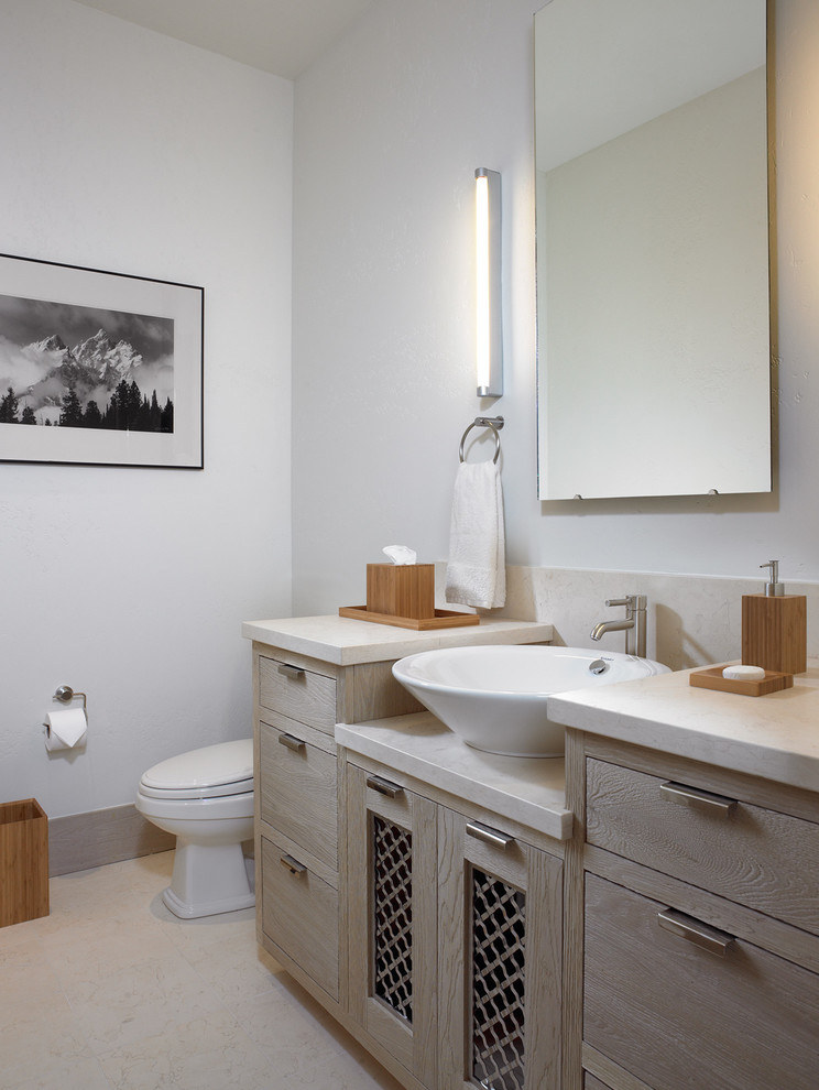 Exemple d'un WC et toilettes montagne en bois clair de taille moyenne avec un placard à porte plane, WC séparés, un mur blanc, un sol en carrelage de céramique, une vasque, un plan de toilette en marbre et un sol beige.