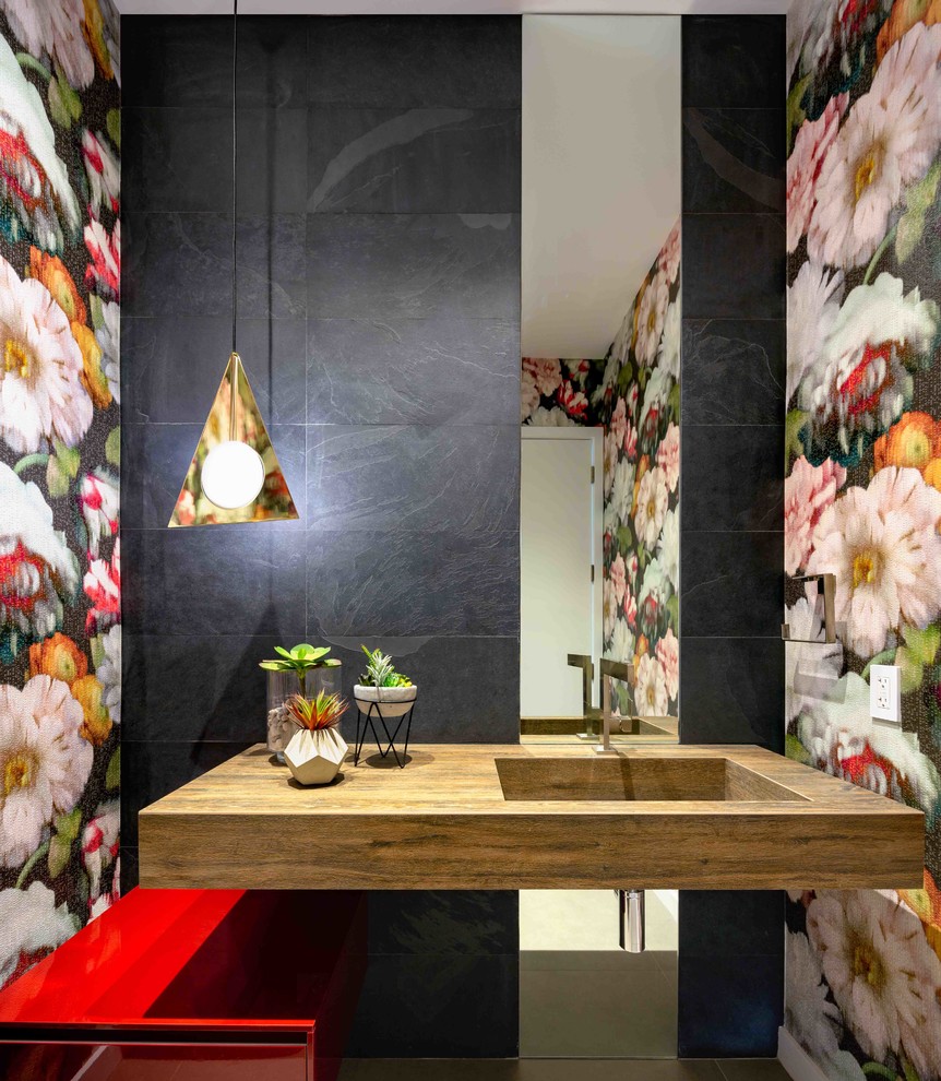 Photo of a small contemporary cloakroom in Miami with flat-panel cabinets, red cabinets, black tiles, porcelain tiles, multi-coloured walls, an integrated sink and brown worktops.