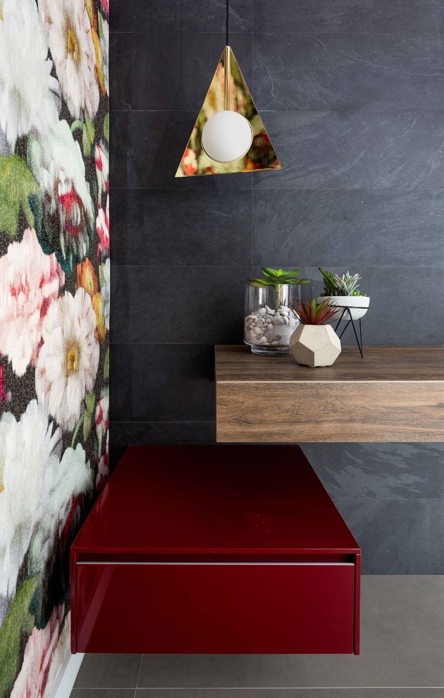 Example of a small trendy black tile and porcelain tile porcelain tile and gray floor powder room design in Miami with flat-panel cabinets, red cabinets, multicolored walls, an integrated sink and wood countertops