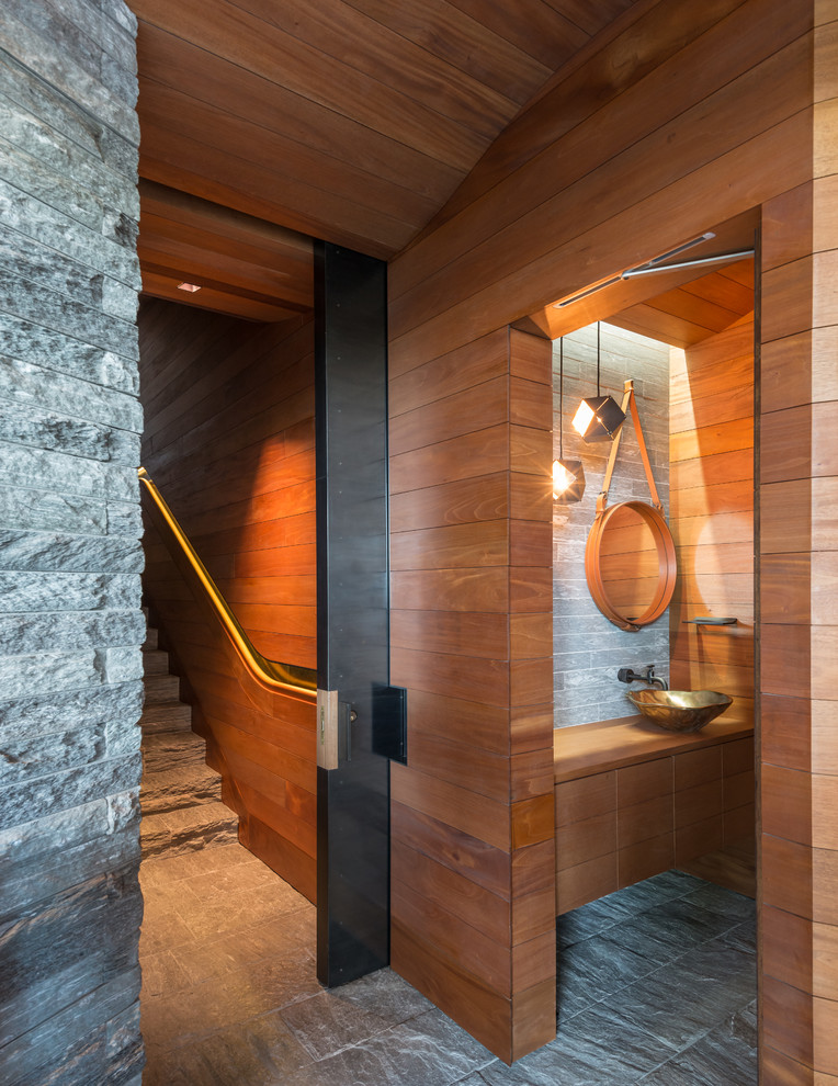 Пример оригинального дизайна: туалет в стиле рустика с настольной раковиной, плоскими фасадами, фасадами цвета дерева среднего тона, столешницей из дерева и серой плиткой