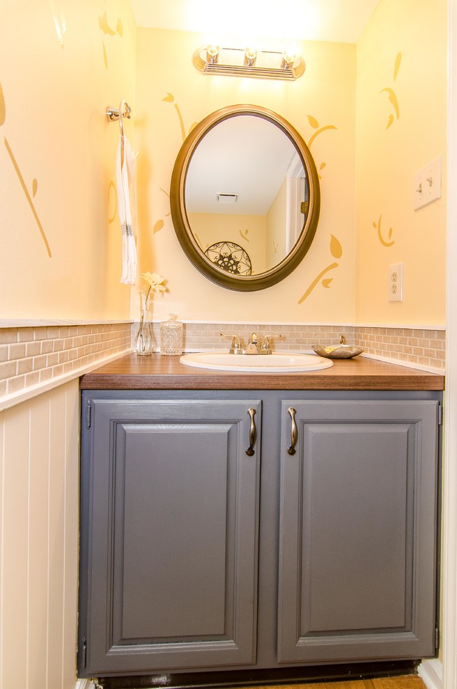 Example of a mid-sized transitional beige tile and ceramic tile powder room design in Philadelphia with a drop-in sink, raised-panel cabinets, gray cabinets, laminate countertops, a one-piece toilet and yellow walls