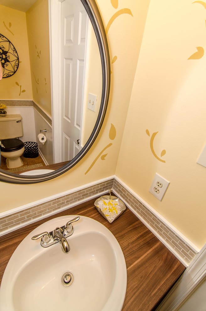Powder room - mid-sized transitional beige tile and ceramic tile medium tone wood floor powder room idea in Philadelphia with a drop-in sink, laminate countertops, a one-piece toilet and yellow walls
