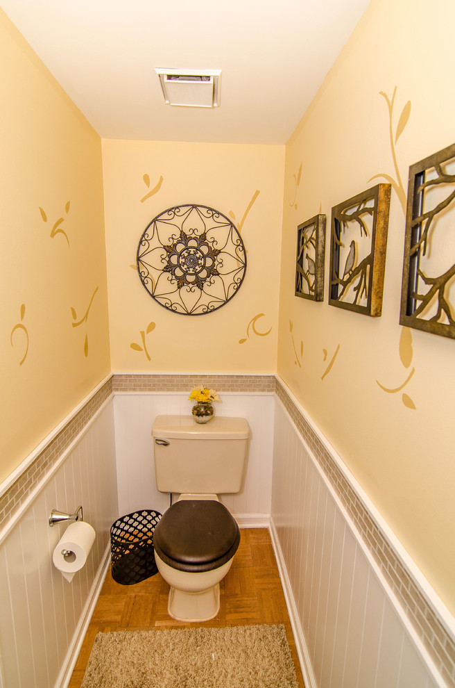 Inspiration pour un WC et toilettes traditionnel de taille moyenne avec un lavabo posé, WC à poser, un carrelage beige, des carreaux de céramique, un mur jaune et un sol en bois brun.