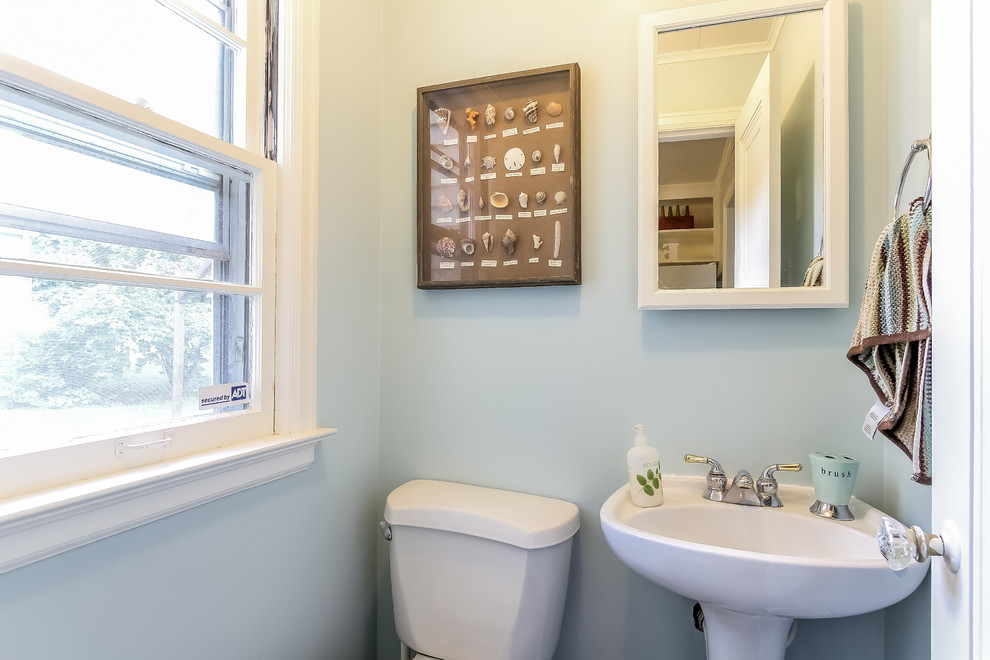 Eklektisk inredning av ett litet toalett, med ett piedestal handfat, en toalettstol med hel cisternkåpa och blå väggar