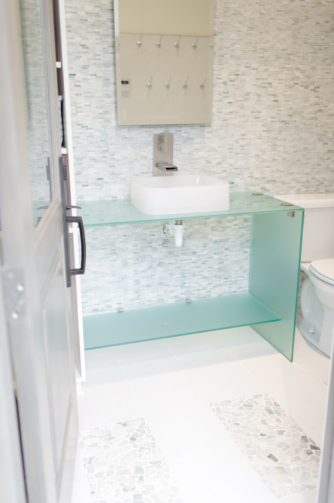 ダラスにある高級な中くらいなトランジショナルスタイルのおしゃれなトイレ・洗面所 (オープンシェルフ、一体型トイレ	、マルチカラーのタイル、モザイクタイル、モザイクタイル、ベッセル式洗面器、ガラスの洗面台、青いキャビネット、白い壁、白い床、青い洗面カウンター) の写真