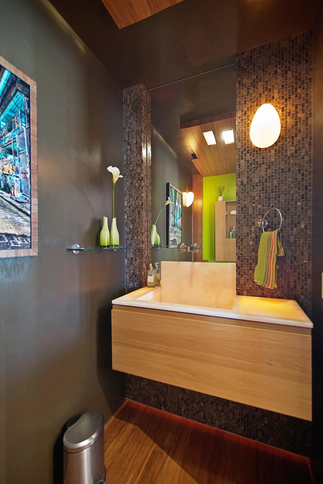 Идея дизайна: туалет среднего размера в современном стиле с плоскими фасадами, светлыми деревянными фасадами, унитазом-моноблоком, коричневой плиткой, плиткой мозаикой, коричневыми стенами, полом из бамбука, монолитной раковиной и столешницей из оникса