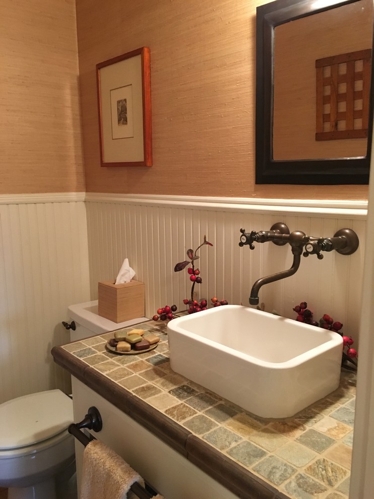 На фото: туалет в стиле кантри с белыми фасадами, разноцветной плиткой, каменной плиткой, коричневыми стенами, настольной раковиной, столешницей из плитки и раздельным унитазом
