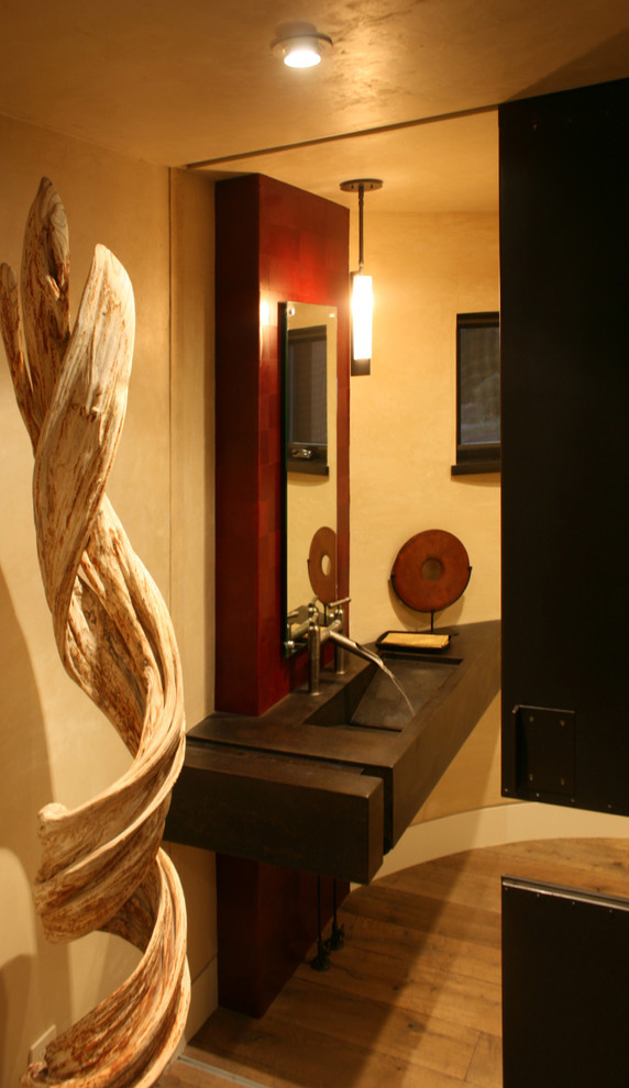Immagine di un bagno di servizio minimal di medie dimensioni con pareti beige, pavimento in legno massello medio, lavabo integrato e top in cemento