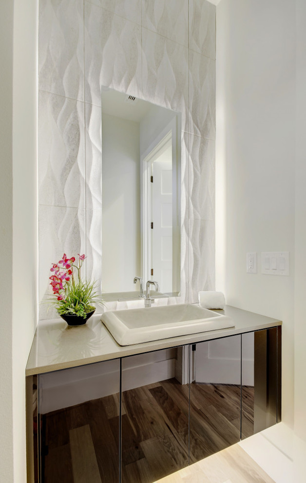 オースティンにあるコンテンポラリースタイルのおしゃれなトイレ・洗面所 (フラットパネル扉のキャビネット、黒いキャビネット、白いタイル、白い壁、オーバーカウンターシンク、ベージュの床、白い洗面カウンター) の写真