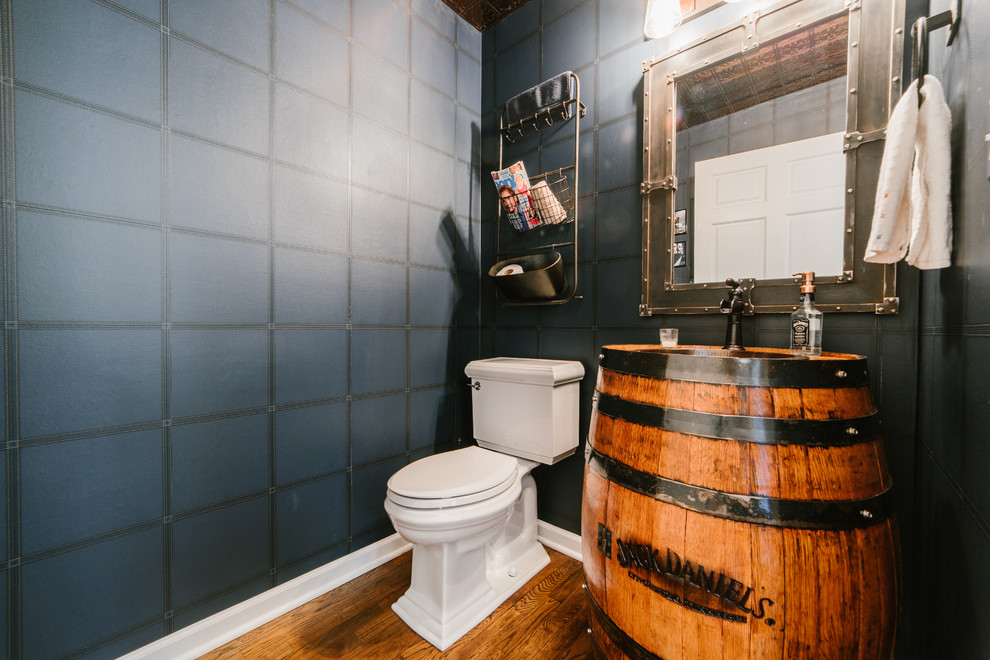 Immagine di un bagno di servizio industriale di medie dimensioni con ante in legno scuro, WC a due pezzi, pareti blu, pavimento in legno massello medio, lavabo da incasso e pavimento marrone