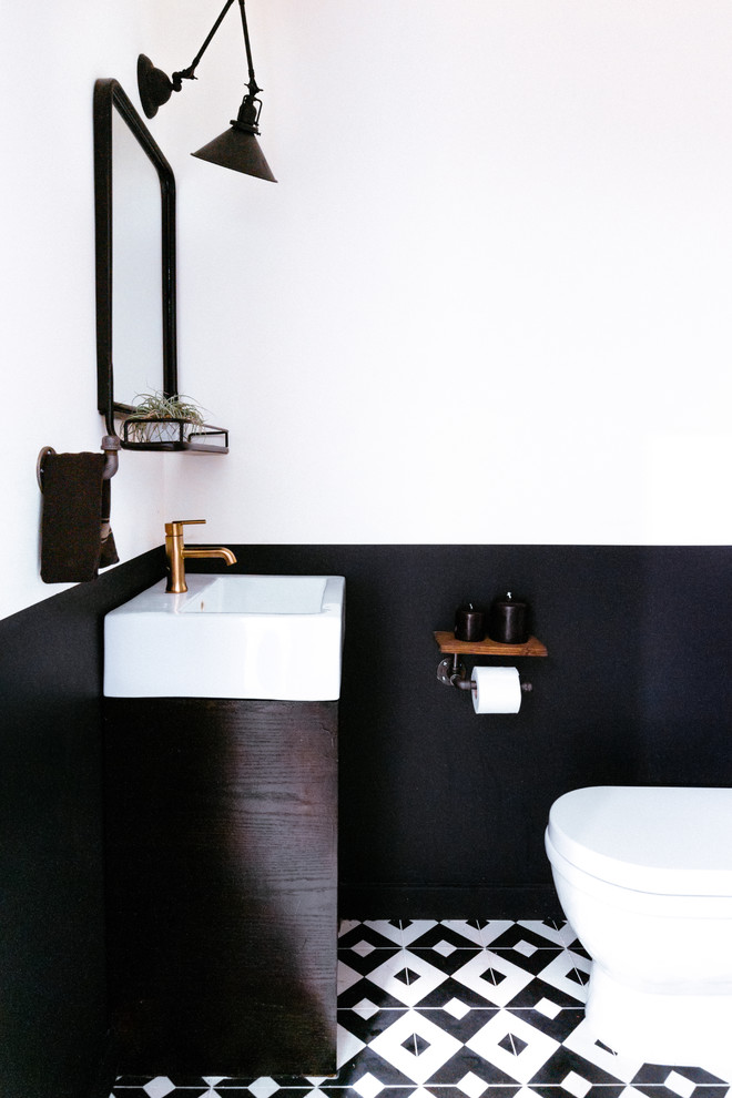 Idee per un piccolo bagno di servizio minimal con WC monopezzo, pistrelle in bianco e nero, piastrelle di cemento, pareti nere, pavimento in cementine e lavabo a consolle