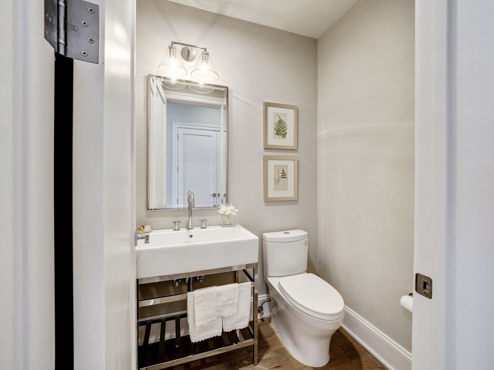 Inredning av ett klassiskt mellanstort toalett, med en toalettstol med hel cisternkåpa, grå väggar, mellanmörkt trägolv, ett konsol handfat och brunt golv