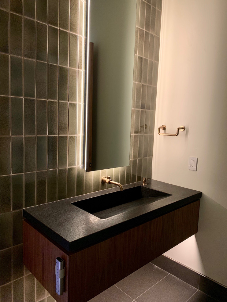 Powder room - modern green tile and porcelain tile porcelain tile and gray floor powder room idea in Sacramento with medium tone wood cabinets, an integrated sink, granite countertops, black countertops and a floating vanity