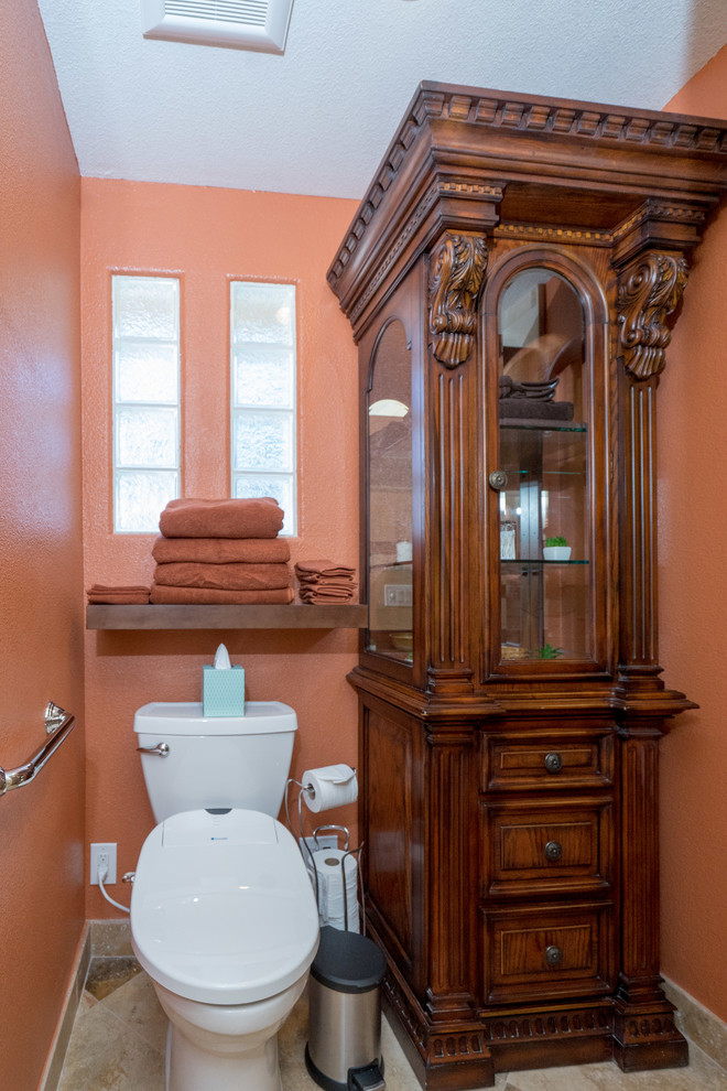 This is an example of a small classic cloakroom in Los Angeles with freestanding cabinets, dark wood cabinets, a two-piece toilet, orange walls and ceramic flooring.