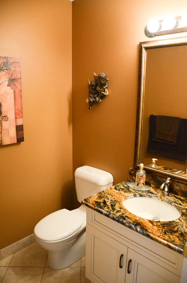 Cette photo montre un petit WC et toilettes chic avec un lavabo encastré, un placard avec porte à panneau encastré, des portes de placard blanches, un plan de toilette en granite, WC séparés, un carrelage beige, un mur marron et un sol en carrelage de céramique.
