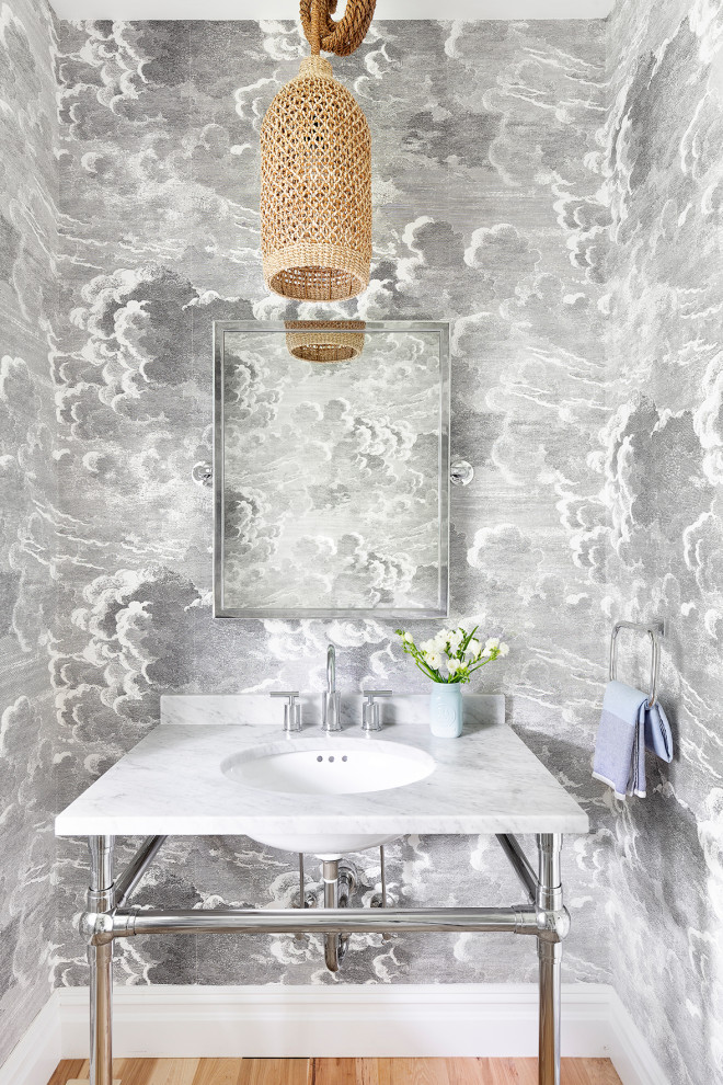 Inredning av ett maritimt vit vitt toalett, med grå väggar, ljust trägolv, ett undermonterad handfat och beiget golv