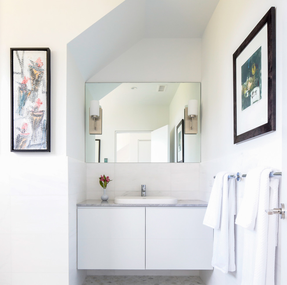 Modern inredning av ett mellanstort toalett, med släta luckor, vita skåp, vita väggar, ett undermonterad handfat och granitbänkskiva