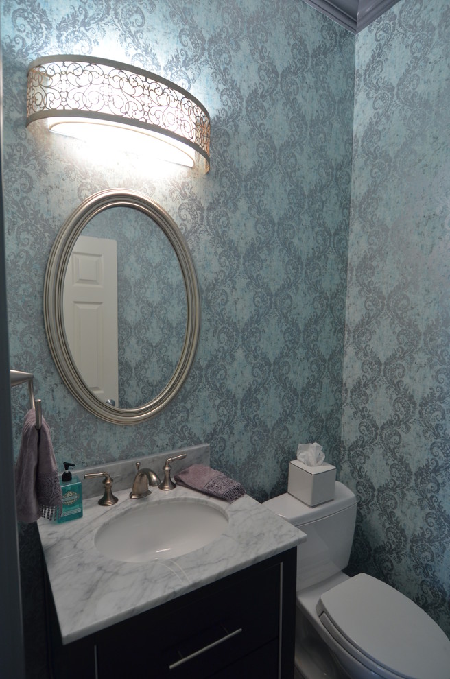 Inredning av ett klassiskt litet toalett, med möbel-liknande, svarta skåp, en toalettstol med separat cisternkåpa, grå kakel, porslinskakel, grå väggar, klinkergolv i porslin, ett undermonterad handfat och marmorbänkskiva