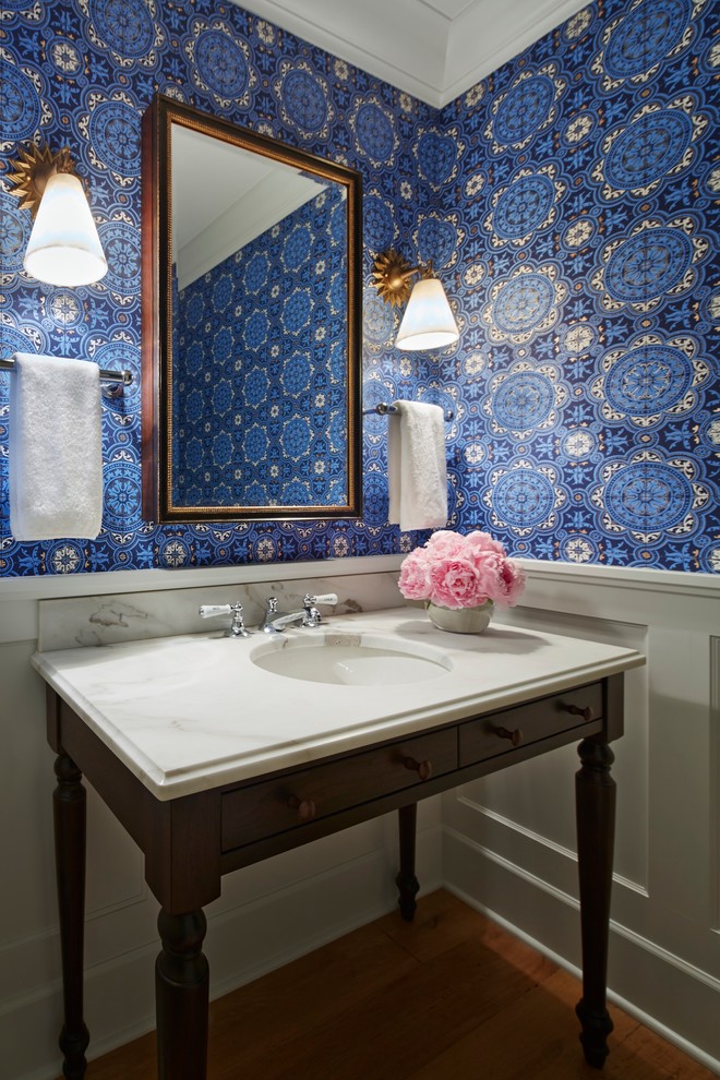 Idées déco pour un WC et toilettes classique en bois foncé de taille moyenne avec un lavabo encastré, un placard en trompe-l'oeil, un plan de toilette en marbre, un mur bleu, un sol en bois brun et un plan de toilette blanc.