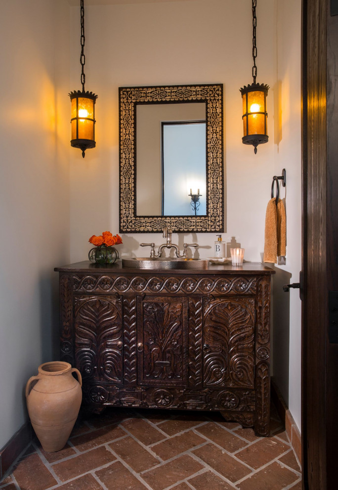 Tuscan terra-cotta tile powder room photo in Phoenix with distressed cabinets, white walls, a drop-in sink, wood countertops, brown countertops and a freestanding vanity