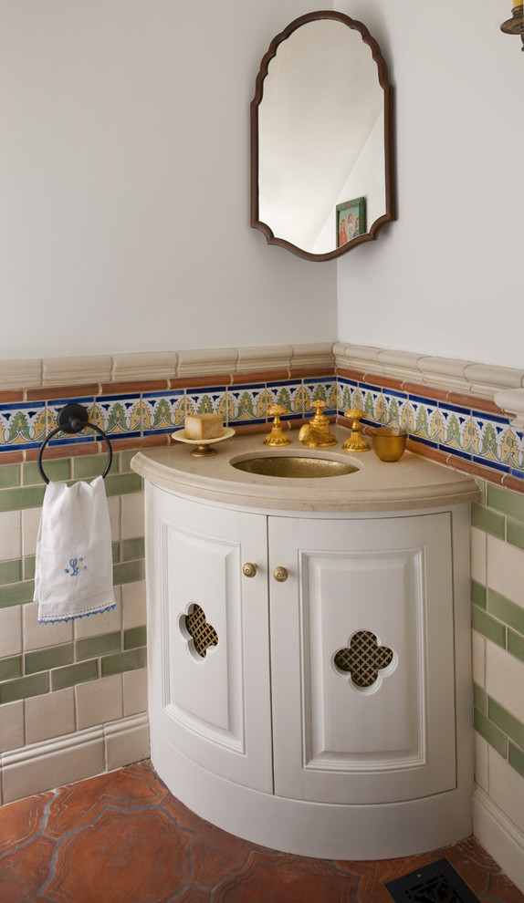 サンディエゴにある小さな地中海スタイルのおしゃれなトイレ・洗面所 (アンダーカウンター洗面器、白いキャビネット、トラバーチンの洗面台、白い壁、テラコッタタイルの床) の写真