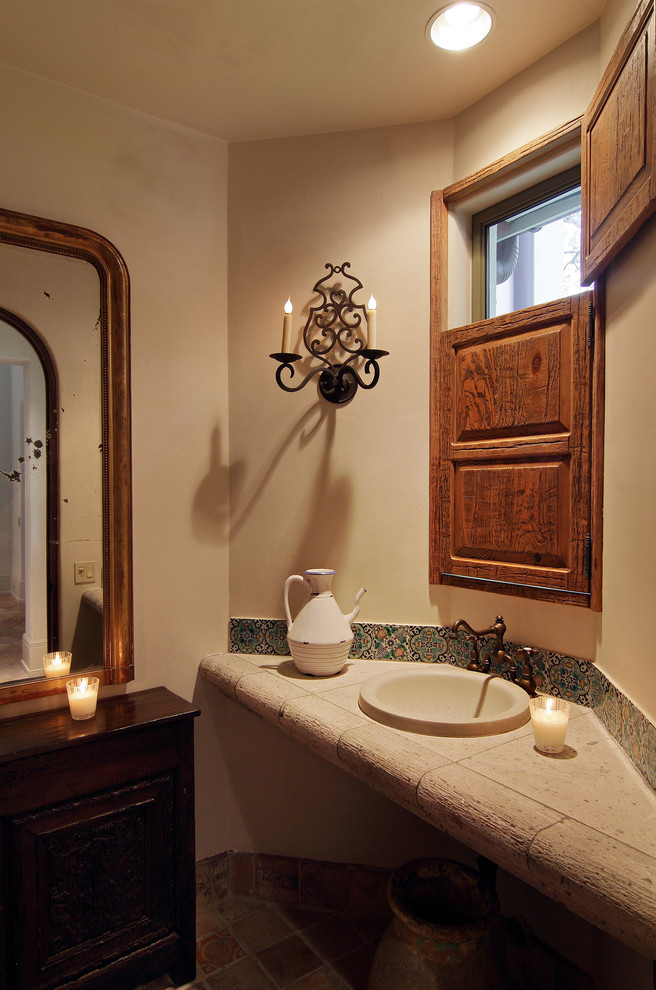 Kleine Mediterrane Gästetoilette mit dunklen Holzschränken, Mosaikfliesen, beiger Wandfarbe, Terrakottaboden, Einbauwaschbecken und gefliestem Waschtisch in Houston