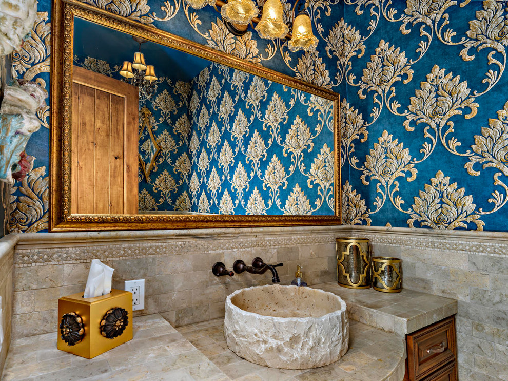 Mittelgroße Mediterrane Gästetoilette mit profilierten Schrankfronten, braunen Schränken, Toilette mit Aufsatzspülkasten, beigen Fliesen, Travertinfliesen, blauer Wandfarbe, Travertin, Aufsatzwaschbecken, Travertin-Waschtisch, beigem Boden und beiger Waschtischplatte in San Diego
