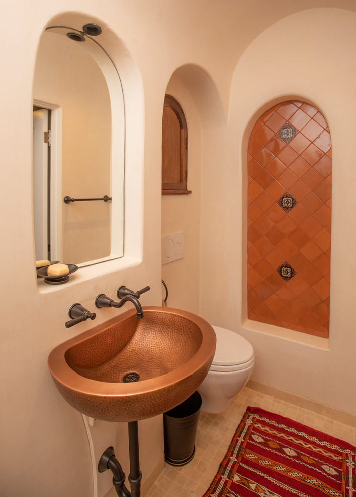 Design ideas for a mediterranean cloakroom in San Francisco with a wall mounted toilet, multi-coloured tiles, orange tiles, beige walls, a wall-mounted sink and beige floors.