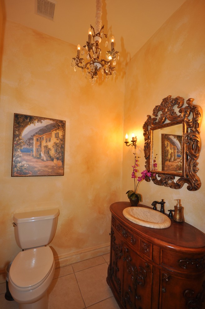 Exempel på ett mycket stort medelhavsstil toalett, med möbel-liknande, skåp i mörkt trä, träbänkskiva, en toalettstol med separat cisternkåpa, beige kakel, gula väggar, travertin golv och ett nedsänkt handfat