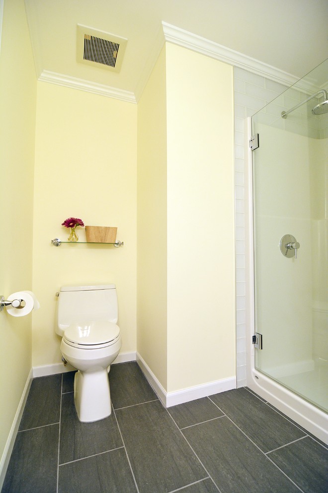 Modern inredning av ett mellanstort toalett, med släta luckor, vita skåp, en toalettstol med hel cisternkåpa, vit kakel, tunnelbanekakel, gula väggar, klinkergolv i keramik, ett undermonterad handfat och granitbänkskiva