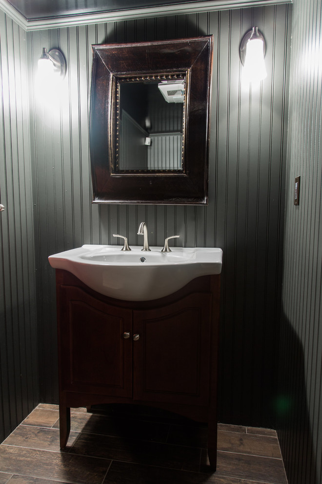 Cette image montre un petit WC et toilettes traditionnel en bois foncé avec un placard sans porte, un mur gris, sol en stratifié, un plan vasque, un plan de toilette en surface solide et un sol marron.
