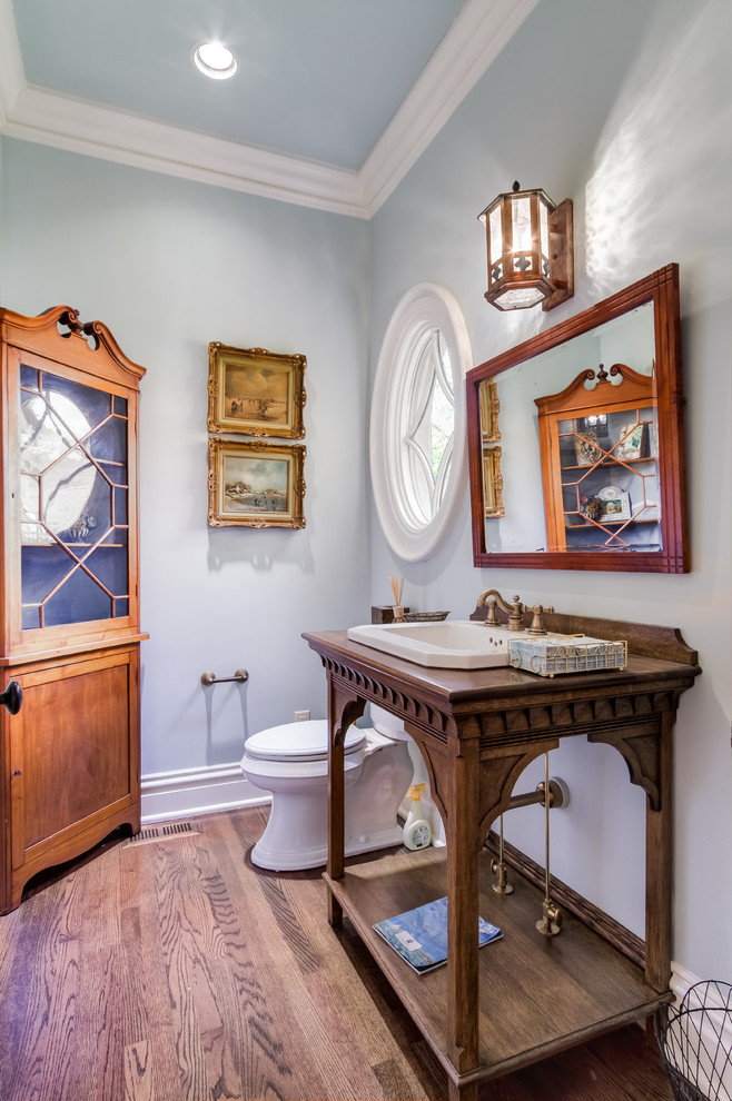 Стильный дизайн: туалет в классическом стиле с накладной раковиной, фасадами островного типа, фасадами цвета дерева среднего тона, столешницей из дерева, раздельным унитазом и синими стенами - последний тренд
