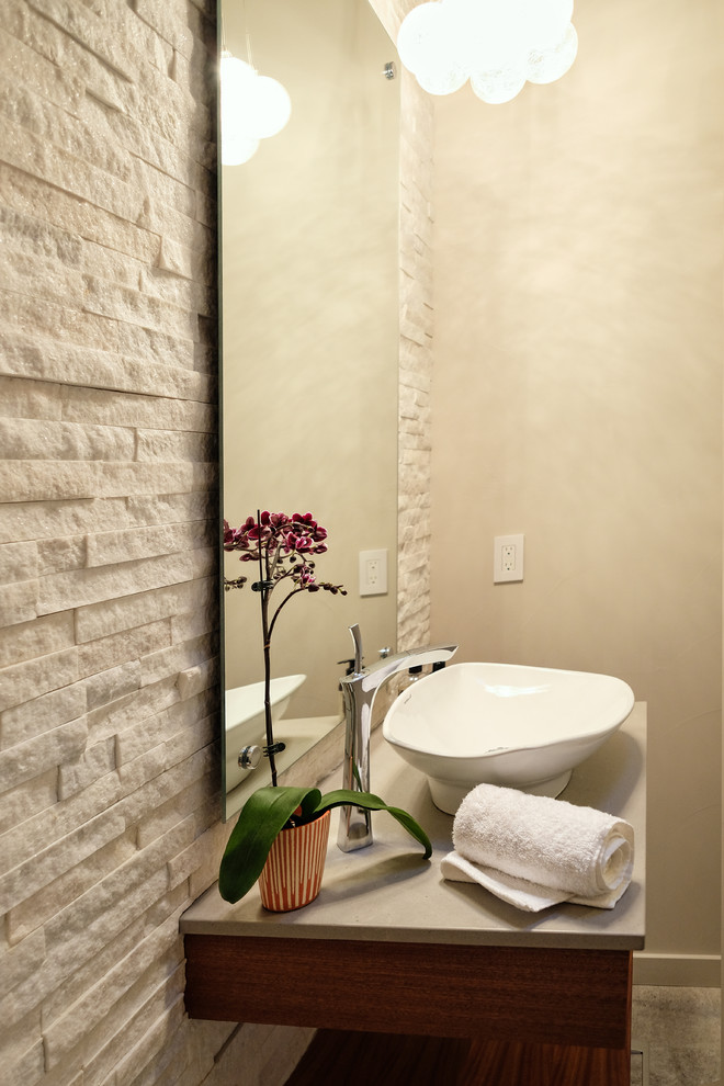 Example of a small trendy beige tile and stone tile porcelain tile and brown floor powder room design in Albuquerque with flat-panel cabinets, medium tone wood cabinets, beige walls, a vessel sink and beige countertops
