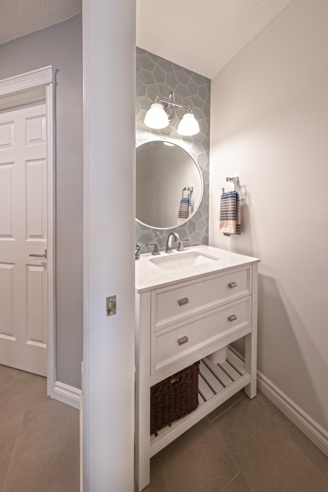 Photo of a small traditional cloakroom in Edmonton with shaker cabinets, white cabinets, a two-piece toilet, grey tiles, ceramic tiles, grey walls, ceramic flooring, a submerged sink, quartz worktops, white worktops, a freestanding vanity unit and grey floors.