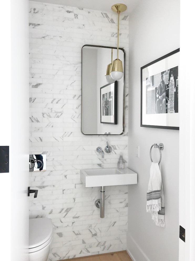 Esempio di un bagno di servizio minimal con WC sospeso, piastrelle bianche, piastrelle di marmo, pareti bianche, pavimento in legno massello medio, lavabo sospeso e pavimento marrone
