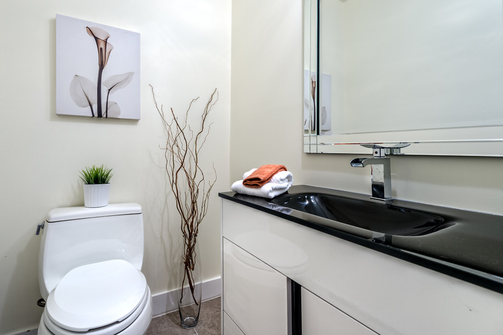 Inspiration for a small contemporary cloakroom in Montreal with flat-panel cabinets, white cabinets, a two-piece toilet, multi-coloured tiles, porcelain tiles, beige walls, porcelain flooring, engineered stone worktops, an integrated sink and black worktops.