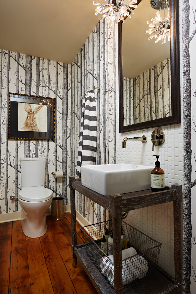 Bild på ett mellanstort vintage brun brunt toalett, med en toalettstol med hel cisternkåpa, vit kakel, porslinskakel, flerfärgade väggar, mörkt trägolv, ett fristående handfat, träbänkskiva och brunt golv